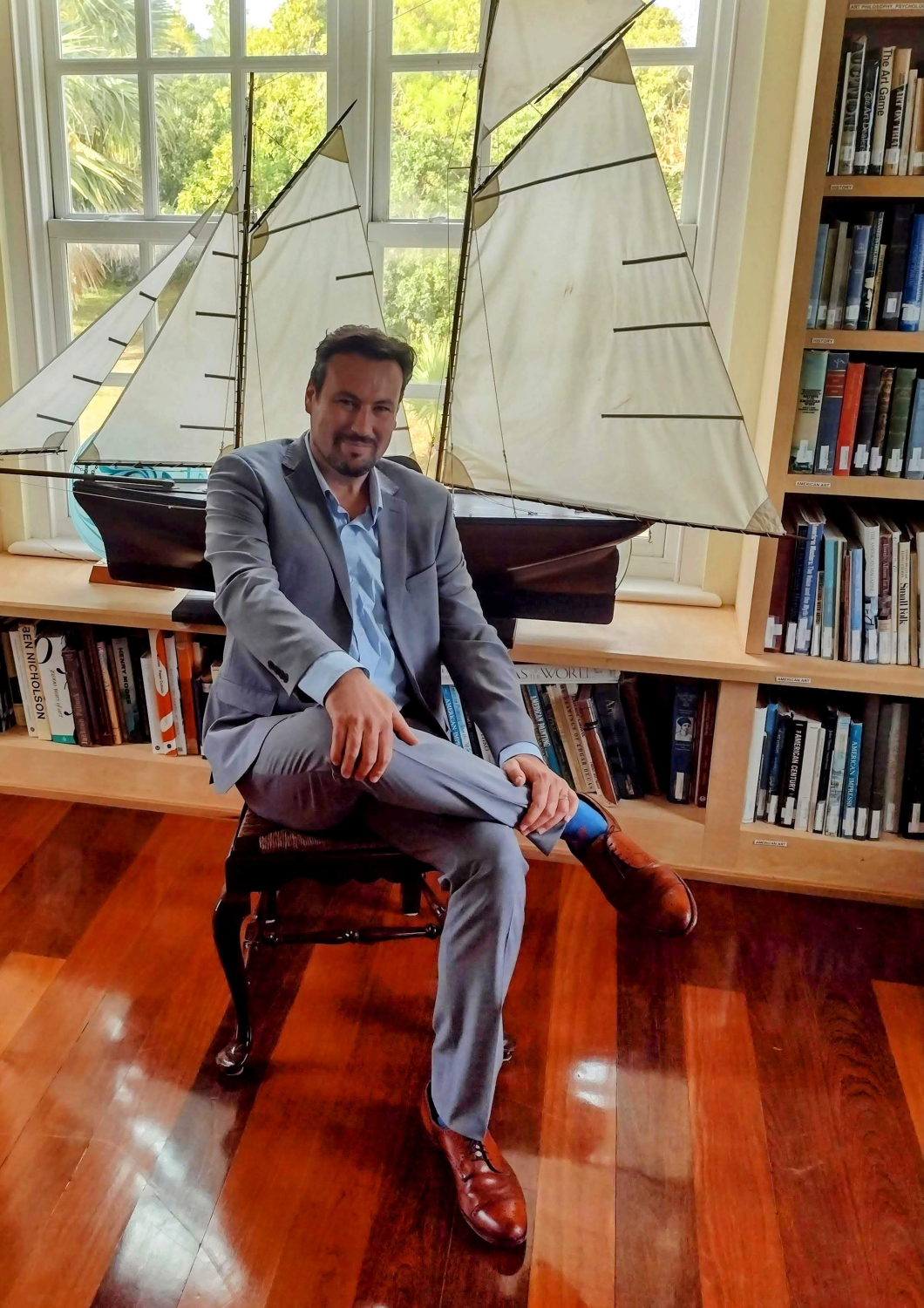 Stephen Cook seated in front of a model sailboat